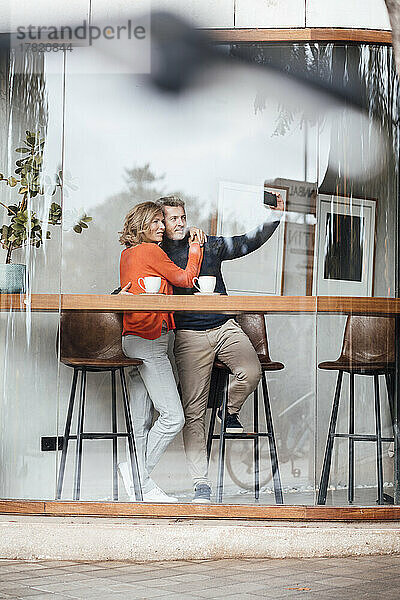 Mann und Frau machen im Café ein Selfie mit dem Handy