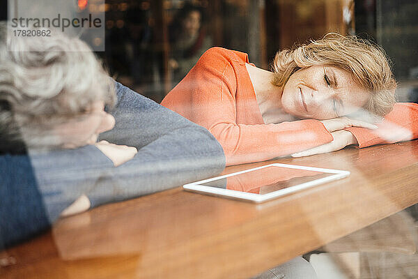 Man with woman sleeping on table in cafe seen through glass