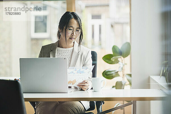 Geschäftsfrau mit Dokument sitzt am Schreibtisch