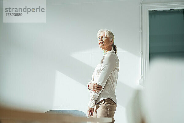Senior businesswoman in front of wall at office