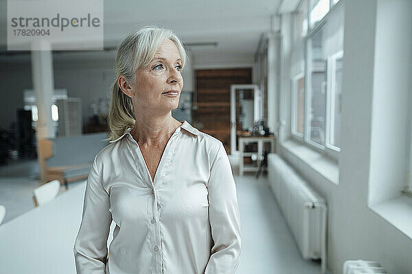 Thoughtful senior businesswoman standing in office