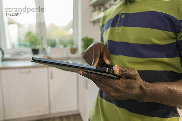 Hände eines Mannes mit Tablet-PC in der heimischen Küche