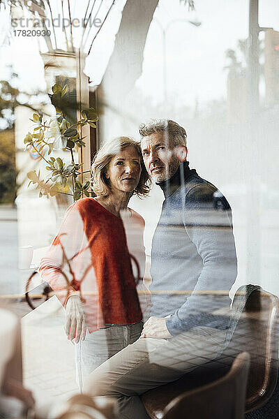 Mann und Frau im Café durch Glas gesehen