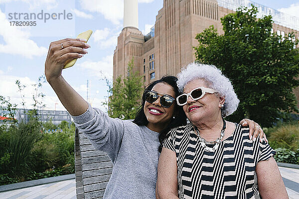 Glückliche Tochter macht Selfie per Handy mit Mutter im Park