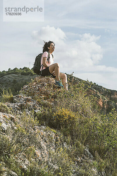 Glückliche Frau mit Rucksack sitzt auf einem Felsen in Aragon  Spanien