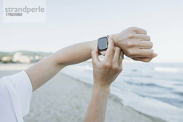 Hand einer Frau mit Smartwatch am Strand