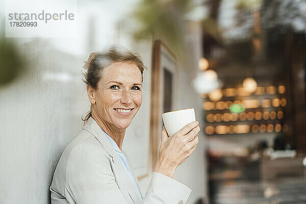 Glückliche Geschäftsfrau hält Kaffeetasse im Café