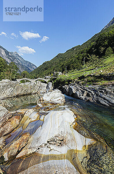 Schweiz  Tessin  Lavertezzo  Fluss Verzasca  der im Sommer durch das Valle Verzasca fließt  mit der Bogenbrücke Ponte dei Salti im Hintergrund
