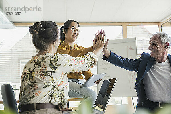 Erfolgreiche Geschäftskollegen geben sich im Büro gegenseitig High-Five