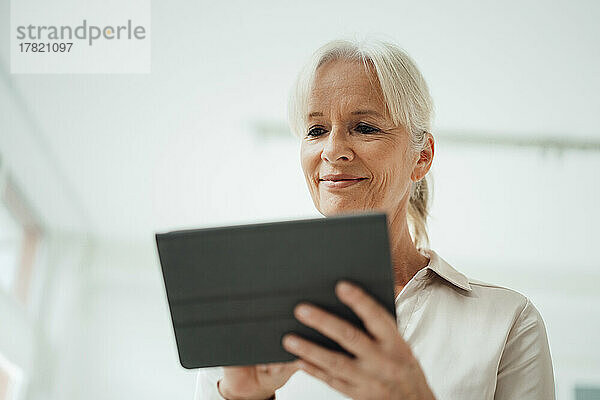 Lächelnde Geschäftsfrau nutzt Tablet-PC im Büro