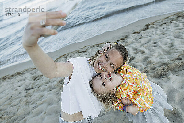 Glückliche Mutter mit Tochter  die am Strand ein Selfie mit dem Smartphone macht