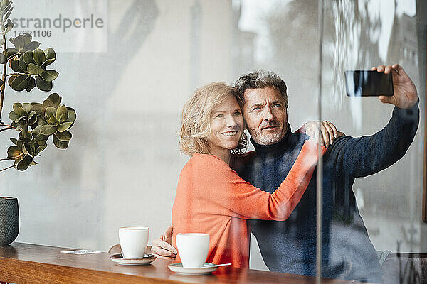 Mann und Frau machen Selfie im Café  gesehen durch das Fenster