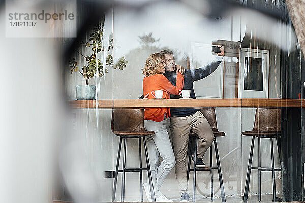 Mann macht Selfie mit Frau per Smartphone im Café