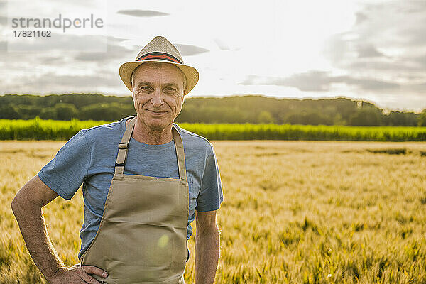 Lächelnder Bauer mit Schürze steht auf dem Bauernhof