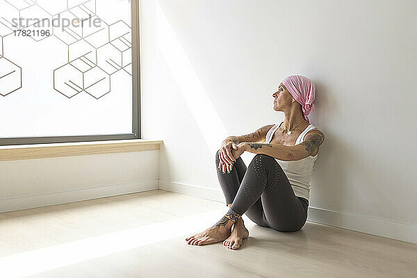 Nachdenkliche Frau mit rosa Schal sitzt zu Hause