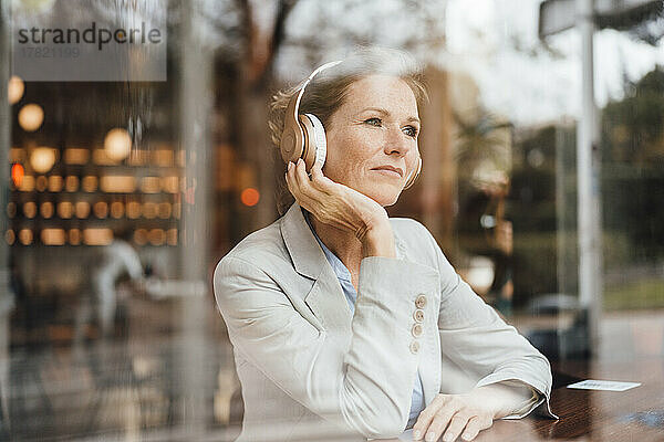 Geschäftsfrau hört im Café Musik über kabellose Kopfhörer