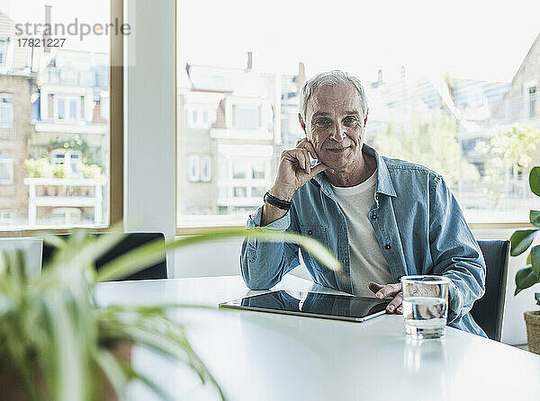 Lächelnder älterer Geschäftsmann mit Tablet-PC am Arbeitsplatz