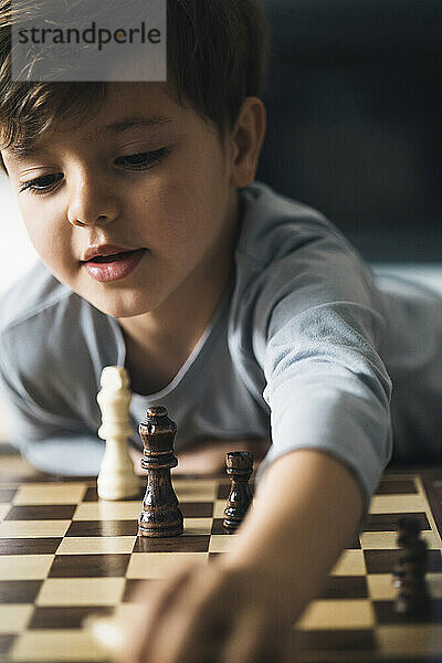 Cute boy playing chess at home