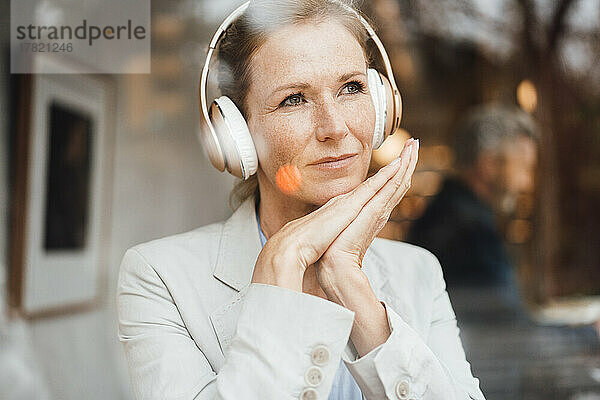 Geschäftsfrau hört im Café Musik über kabellose Kopfhörer