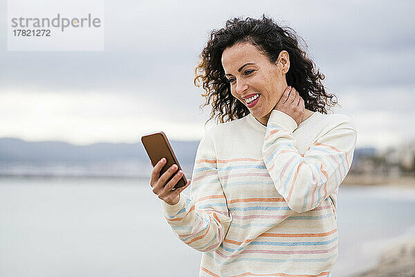 Glückliche Frau  die ihr Mobiltelefon auf dem Seeweg benutzt
