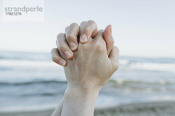 Hände vor dem Meer am Strand gefaltet