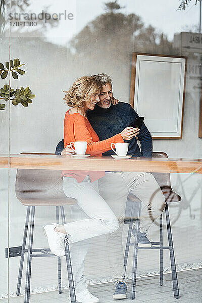 Lächelnde Frau und Mann machen Selfie per Smartphone im Café