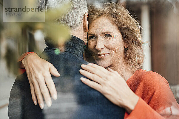 Smiling woman hugging man in cafe