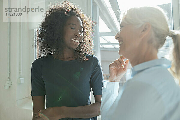 Smiling senior businesswoman talking with colleague in office
