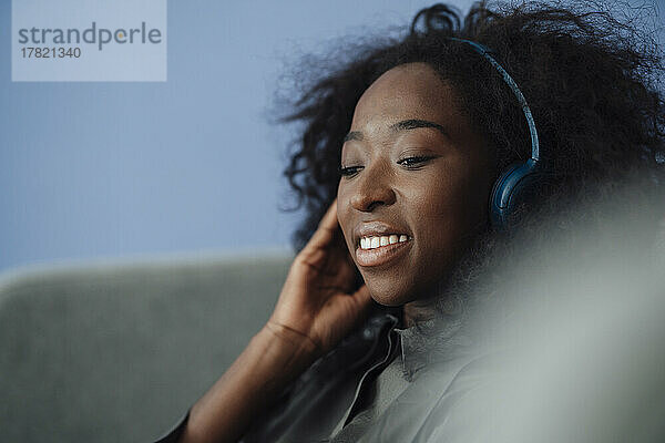 Lächelnde junge Frau  die über kabellose Kopfhörer Musik hört