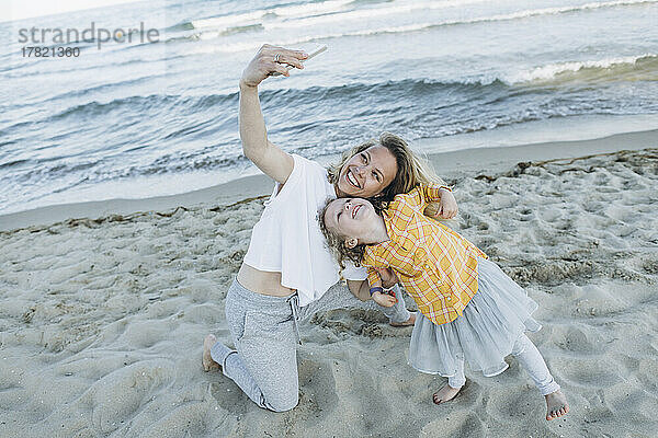 Glückliche Mutter macht Selfie mit Tochter am Strand