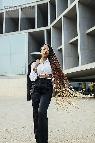 Selbstbewusste junge Geschäftsfrau mit langen braunen geflochtenen Haaren