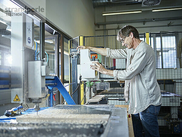 Reifer Mann arbeitet an Holzmaschine in der Fabrik