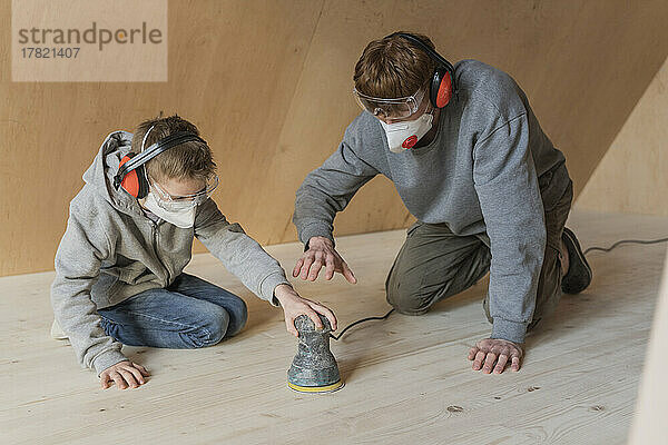 Vater und Sohn schleifen den Boden in ihrem neuen Öko-Haus