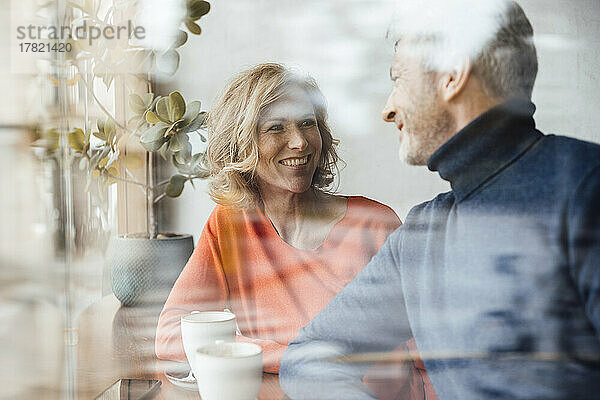 Smiling woman with man in cafe seen through glass