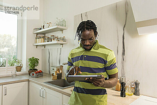 Mann benutzt Tablet-PC in der Küche