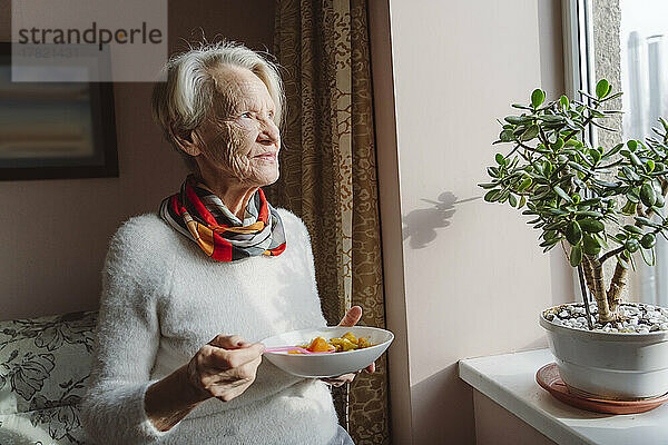 Ältere Frau mit Schüssel am Fenster
