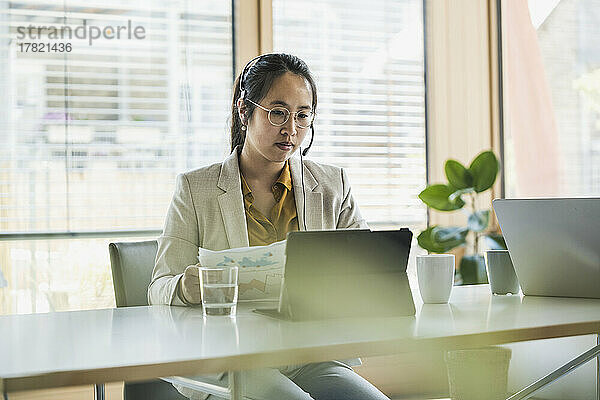 Geschäftsfrau mit Headset arbeitet am Tablet-PC im Büro