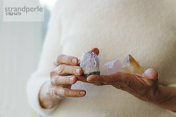 Hände einer älteren Frau  die Kristallsteine ??hält