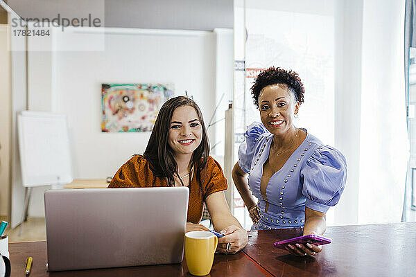 Lächelnde Geschäftsfrauen mit Smartphones im Büro