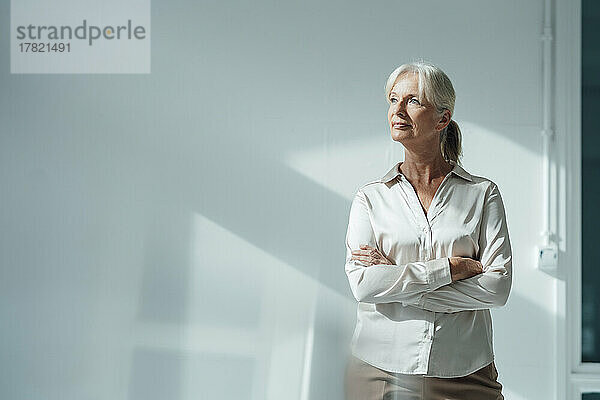 Senior businesswoman standing with arms crossed in office