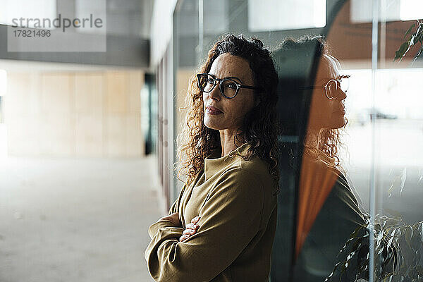 Frau mit Brille lehnt an Glas