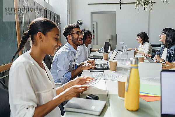 Zufriedene  gemischtrassige Geschäftskollegen  die am Schreibtisch im Coworking-Büro arbeiten