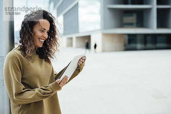 Lächelnde Geschäftsfrau mit Tablet-PC  die an der Stange steht