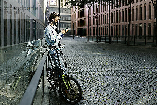 Lächelnder Mann  der sein Mobiltelefon auf der Straße benutzt