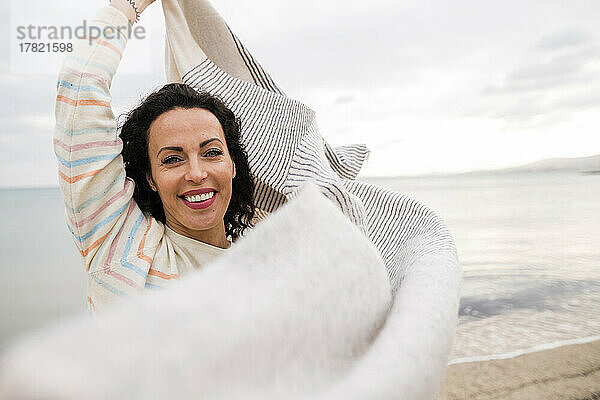Lächelnde reife Frau mit Schal am Strand
