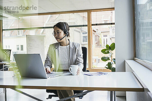 Lächelnde Geschäftsfrau  die im Büro am Laptop arbeitet