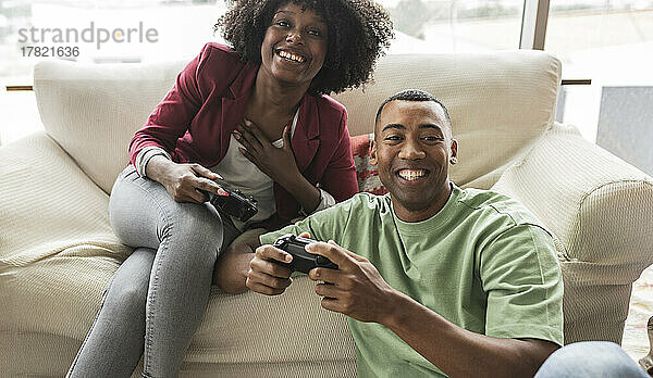 Glückliche junge Frau spielt Videospiel mit Mann
