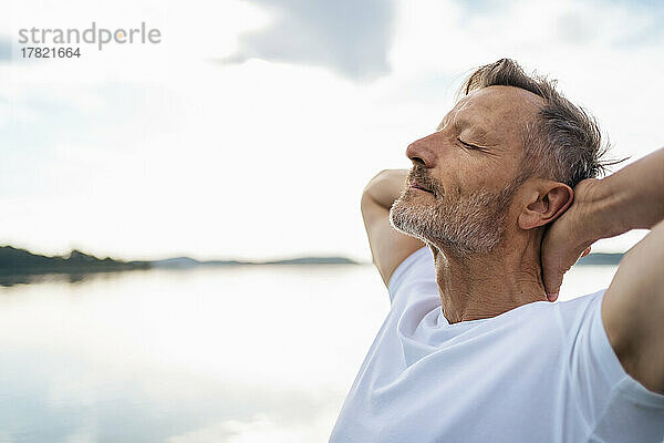 Reifer Mann entspannt sich mit geschlossenen Augen am See