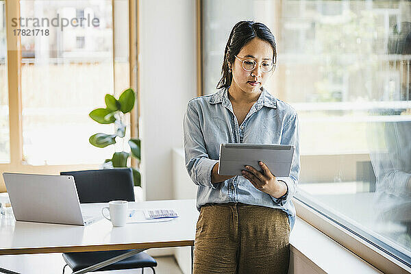 Geschäftsfrau nutzt Tablet-PC am Fenster im Büro