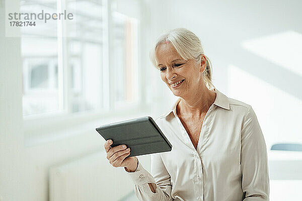 Smiling businesswoman holding tablet PC in office